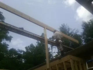 Carpenter setting a ridge beam over a new addition frame — Ice Dam Removal by Roofing Brothers in Pass Christian