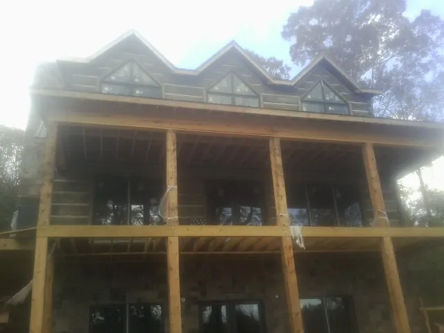 Dormers and porch framing on a large log home under construction — Roof Coating work by our crew in Pass Christian