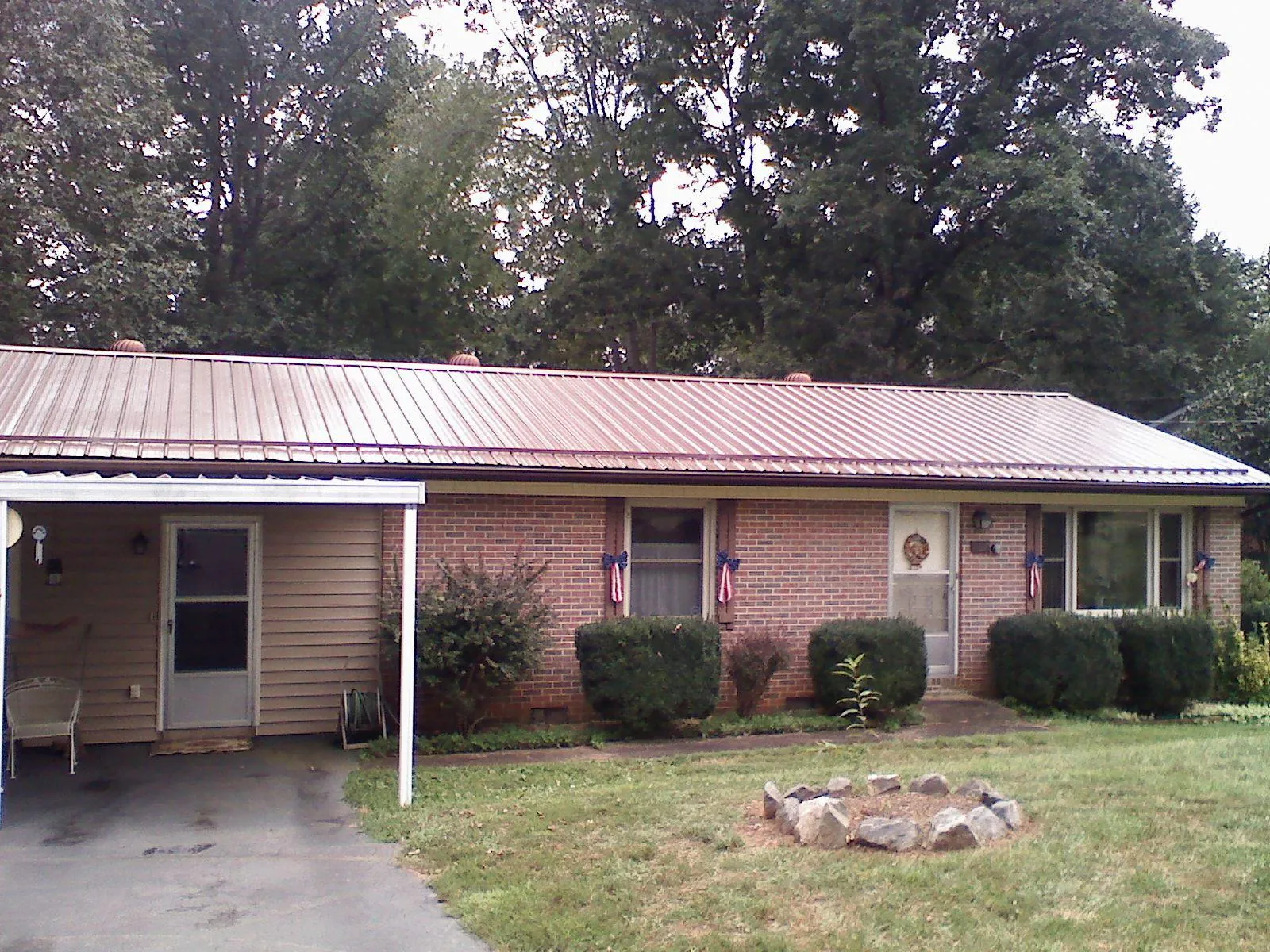 Bronze metal roof and carport on a brick ranch home — Roof Repair work by our crew in Pass Christian