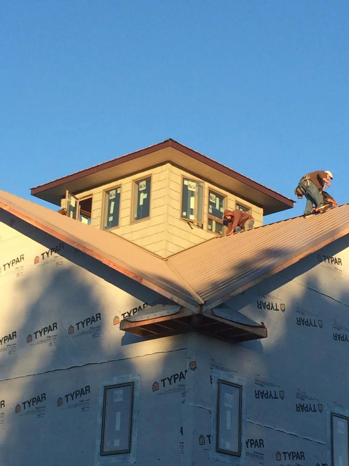 Roofers working around a rooftop cupola on a new metal roof at sunset — Roof Waterproofing in Pass Christian by Roofing Brothers